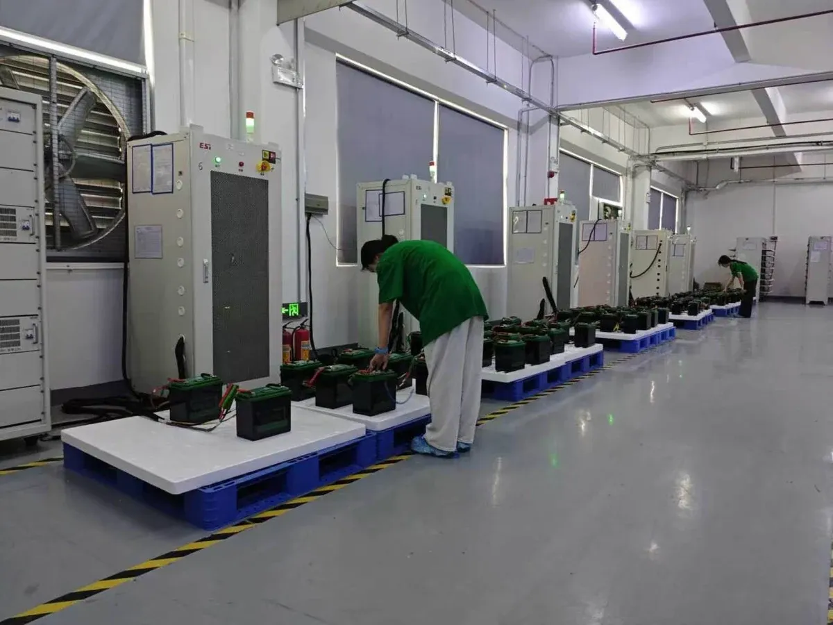 Technicians working with connected battery packs beside inspection equipment