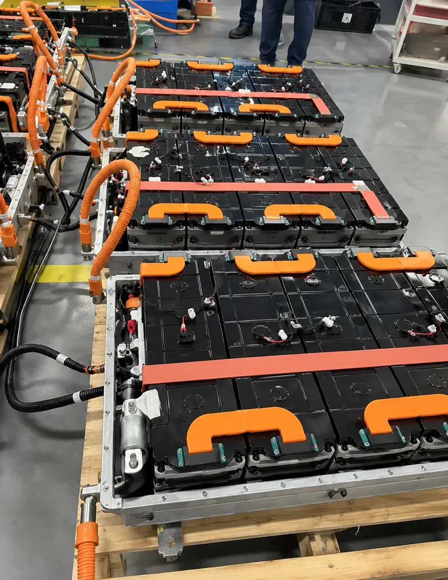 Mining Truck Battery Pack Assembly and High-Voltage Integration Reference | TUORDE Mining equipment battery-pack assembly reference showing black modules and orange high-voltage cables in a workshop